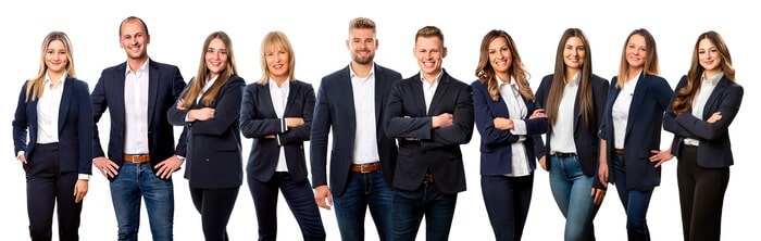 Eine Gruppe von zehn jungen Erwachsenen, Männern und Frauen, in legerer Geschäftskleidung mit Blazern und Jeans, die in einer Reihe stehen und selbstbewusst vor einem weißen Hintergrund lächeln.