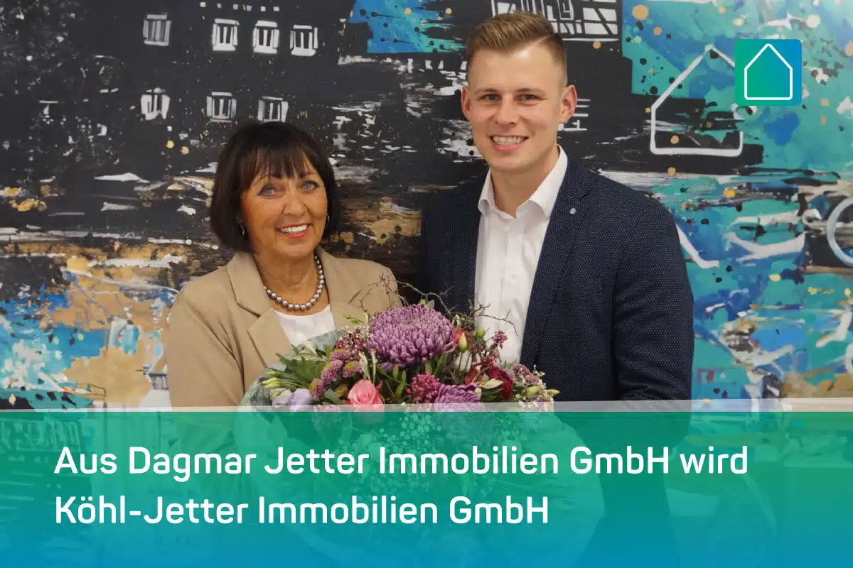 Eine lächelnde Frau und ein Mann im Geschäftsanzug halten einen großen Blumenstrauß. Hinter ihnen ist ein abstraktes Wandgemälde zu sehen. Der Text lautet: Aus Dagmar Jetter Immobilien GmbH wird Köhl-Jetter Immobilien GmbH.